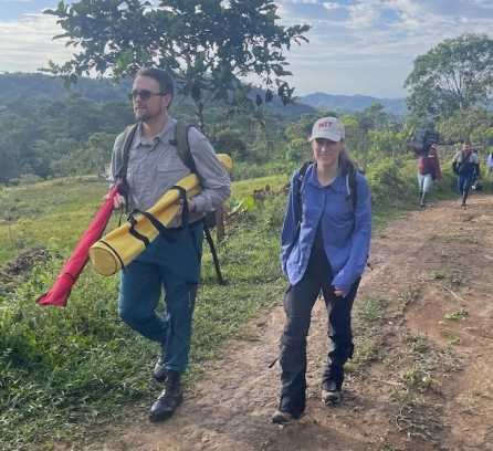 Sean Anklam and Marcela Angel lead a larger group down a dirt road in a verdant, mountainous area of Colombia