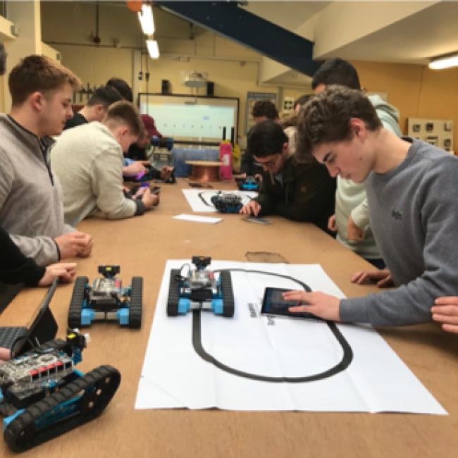 Students working with small robots and laptops