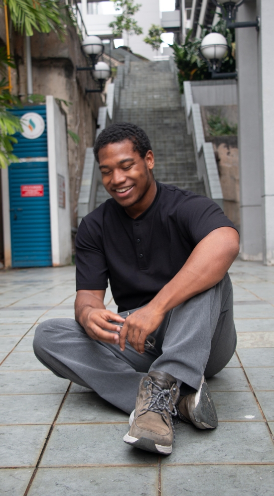 Zachary Francis sitting in an alleyway with a staircase behind him 