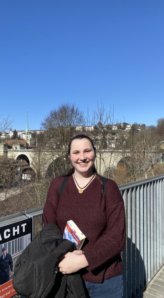 Mid shot of Aquila Simmons standing by a fence with the city of Bern, Switzerland, in the background with bald trees