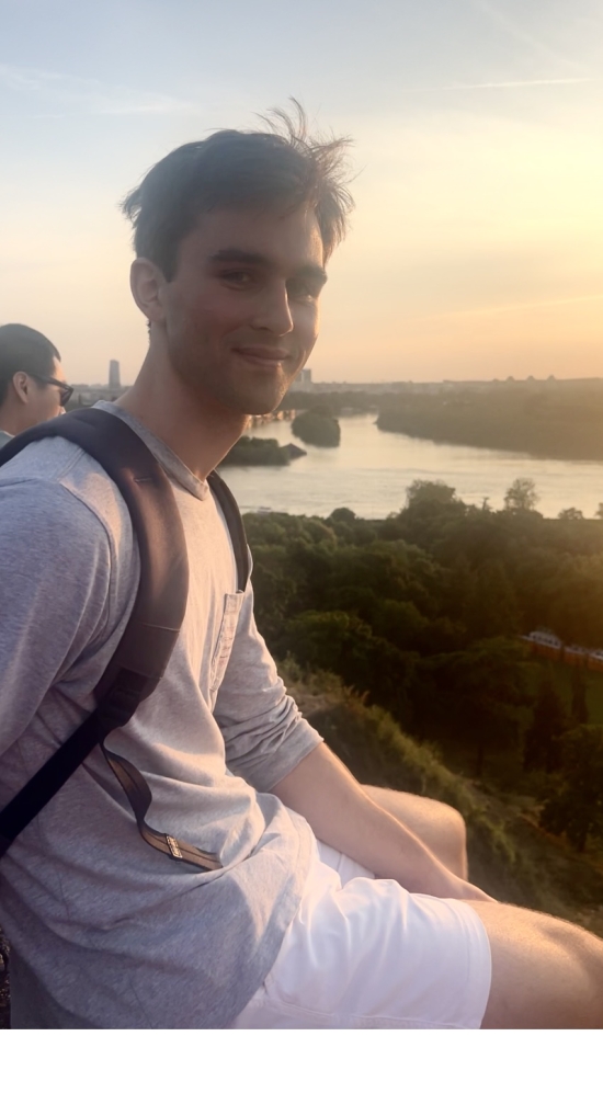 Graham Guite sitting with a view of the sunset, river and luscious green trees below