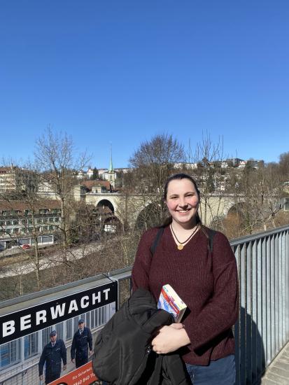 Mid shot of Aquila Simmons standing by a fence with the city of Bern, Switzerland, in the background with bald trees