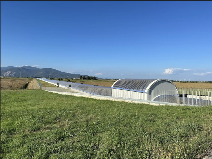 Pisa Lab in a vast countryside in Italy surrounded by grass and a few mountain peaks in the background and clear blue sky